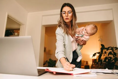 Design professional making notes while holding her baby Foto stock