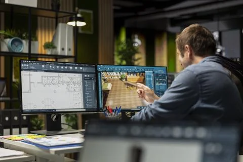 Design specialist using modeling software and blueprints on computer 库存照片