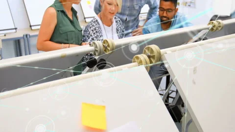Design team examining pulley model in design studio, displaying digital node Stock Footage 308655953