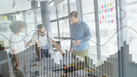 Design team grouping around table, center person pointing, causing live charts Stock Footage 334693999
