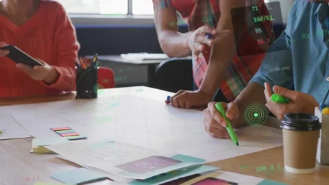 Design team tapping phone and marking mockups, refining layout on table, causing Stock Footage 333351150