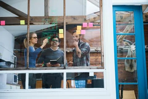 Design team writing on adhesive notes and drawing on design studio window Foto stock