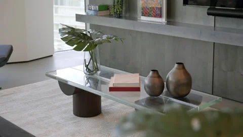 Designed table made of glass surface and hardwood legs standing on light rug in Video stock 282256500