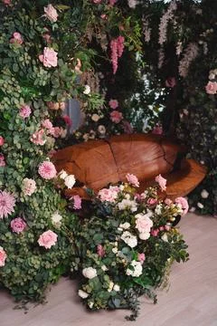 Designer bench made of a tree trunk in a garden interior with floral decorati Stock Photos
