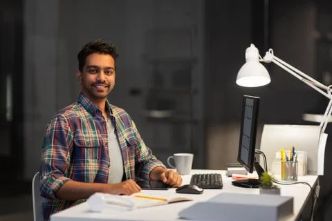 Designer with computer working at night office Foto stock