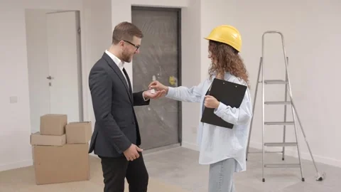 Designer with documents giving keys from apartment to businessman Stock Footage 330535103