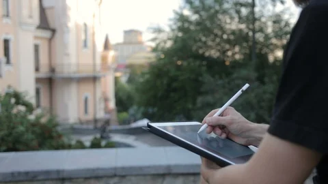 Designer drawing a sketch on tablet using stylus at park Video stock 92581137