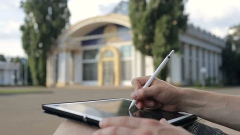 Designer drawing a sketch on tablet using stylus at park Video stock 92581151