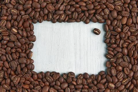 Designer frame made of coffee beans on a blue wooden table. Presentation mockup Stock Photos