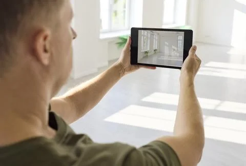 Designer holding tablet while assessing bright interior room layout in modern Stock Photos