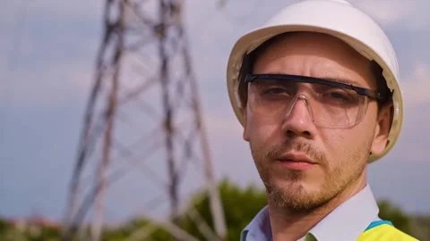 A designer inspects a high voltage tower. An engineer in a hard hat servicing a Stock Footage 252667348