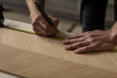 A designer man using his measuring tape to measure a piece of veneer wood 스톡 사진