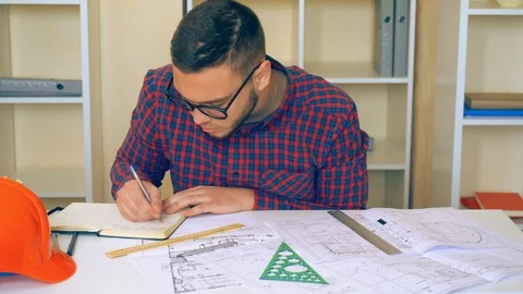 Designer or engineer sitting at the desk with drawing Stock Footage 86250585