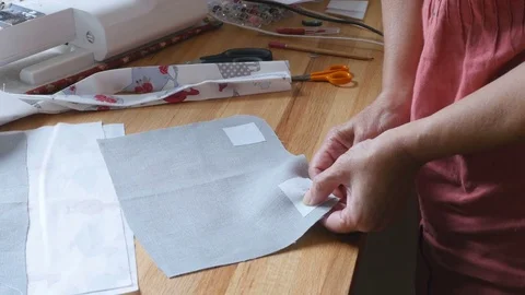 Designer preparing fabric so that she can add buttons to her design Stock-Footage 77229985