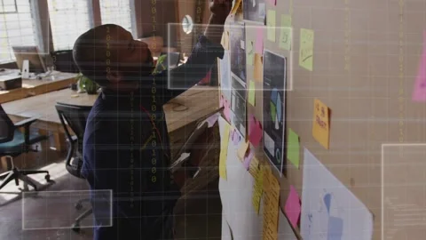 Designer reading clipboard then annotating board, organizing plan with notes and 库存影片 334768487
