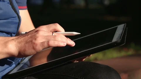 Designer search references for his work at park on tablet. Stockbeeldmateriaal 82360442