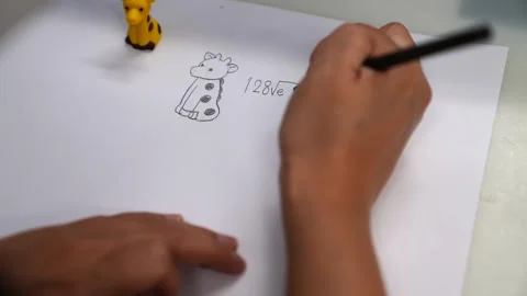 Designer sketching a giraffe pattern on paper beside a colorful giraffe shaped Stock Footage 343370829