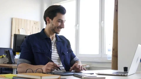 Designer sketching on tablet sitting at table in office Stock Footage 72872194