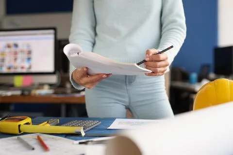 Designer stands next to work table and holds papers and pencil Stock Photos