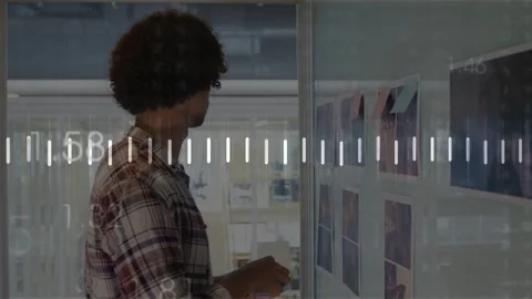 Designer studying grid on glass planning layout placing notes while using phone Stock Footage 333154050