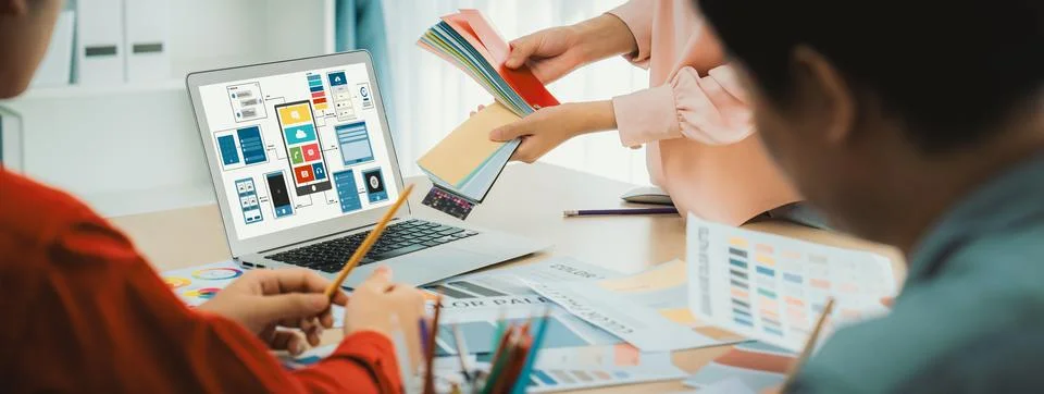 Designer team present color while laptop displayed UI and UX designs Variegated. Stock Photos