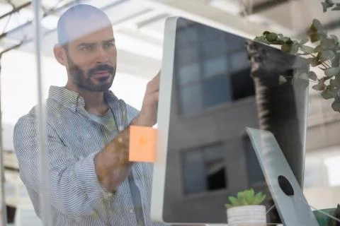 Designer using computer in studio seen through glass Foto stock