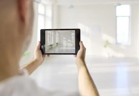 Designer using tablet to photograph bright modern interior room in spacious hall Stock Photos