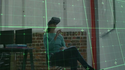 Designer using VR headset sitting in tech office, interacting with neon green Stock Footage 308572895