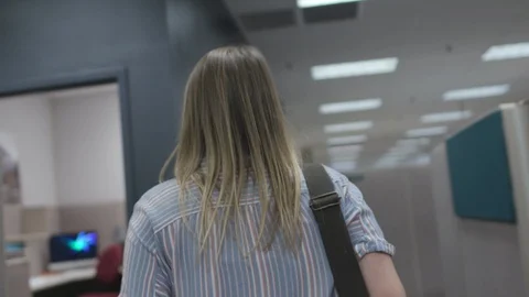 Designer Walks Through Cubicles and Sits At Desk Stock Footage 122934772