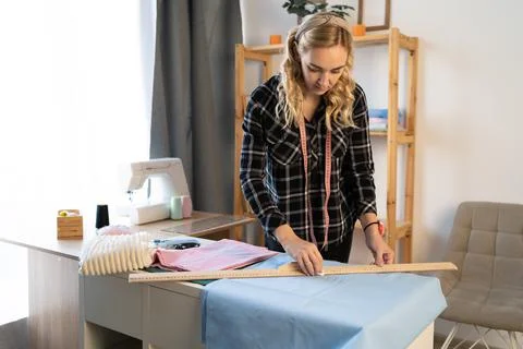 Designer at work with fabric in workshop. Tailor measuring necessary amount of Stock Photos