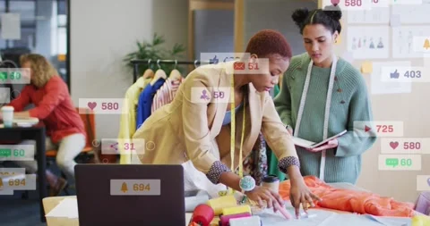 Designers adjusting fashion patterns for web buzz as laptop alert creating Stock Footage 329929682