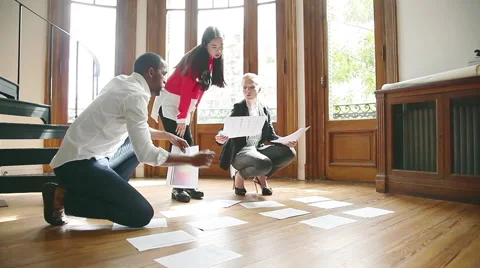 Designers brainstorming, arranging documents on floor Stock Footage 63275300
