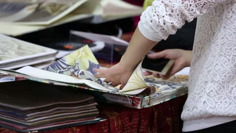 Designers browsing and viewing catalogues with home interiors and materials for Stock Footage 88432841