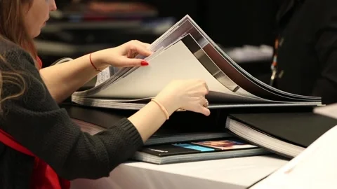 Designers browsing and viewing catalogues with home interiors and materials for Stock Footage 88432867