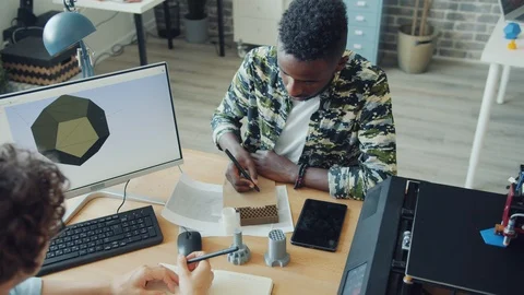 Designers discussing 3d printer models using computer in modern office Stock Footage 119556186