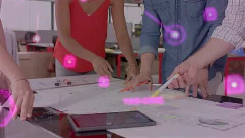 Designers leaning over plans hands reaching and placing notes pink overlay Stock Footage 333911380