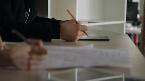 Designers sit at same table and consider building plans on paper at each other Stock Footage 64966786