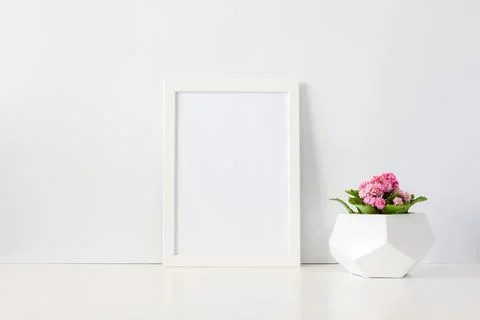Desk against a white empty wall with a plant with pink flowers in a geometric Stock Photos