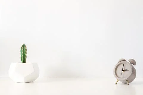 A desk against a white empty wall with a cactus in a geometric pot Stock Photos