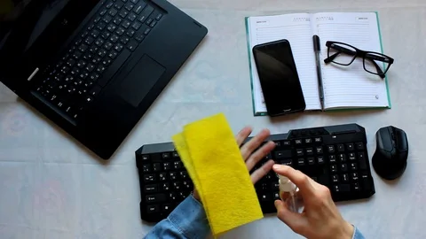 A desk with a computer mouse and keyboard. a man sprays an antiseptic on a Stock Footage 129462807