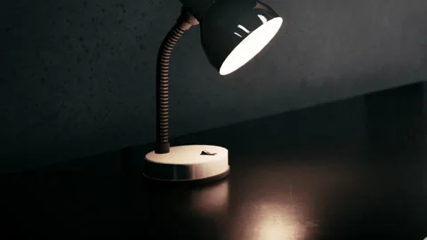 Desk lamp on a dark surface in a well lit room Stock Footage 348558442