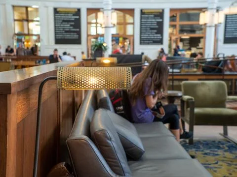 Desk lamp at table of crowded train station with woman traveler sitting Stock Photos