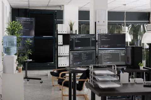 Desk with multiple pc monitors compiling terminal window Stock Photos