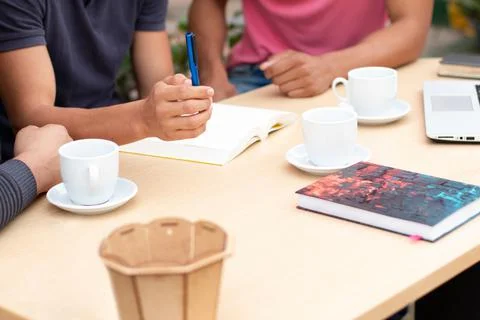 Desk with objects for study and work. hands of unknown persons talking. Stock Photos