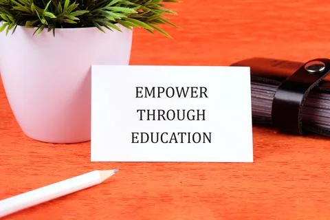 Desk setup includes a card that says empowering education, a plant, and a not Stock Photos