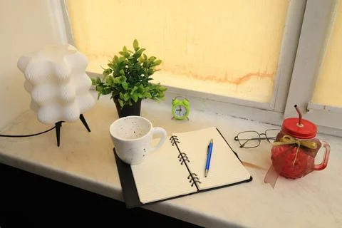 Desk setup with lamp, notebook, coffee cup, and drink jar Stock Photos