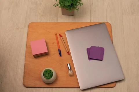 Desk setup with laptop, sticky notes, pens, and small plant Stock Photos