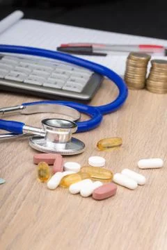 A desk with a stethoscope and objects that relate to health care costs Foto stock