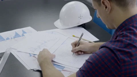 At desk there is an engineer working on a construction project on documents. Video stock 85711588