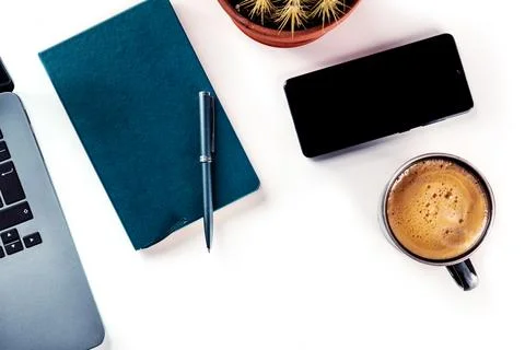 Desk, top view on a white background. Coffee, notebook, phone, plant Stock Photos